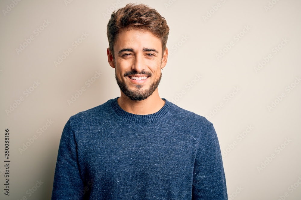 Young handsome man with beard wearing casual sweater standing over white background with a happy and cool smile on face. Lucky person. Young handsome man with beard wearing casual sweater standing over white background with a happy and cool smile on face. Lucky person.