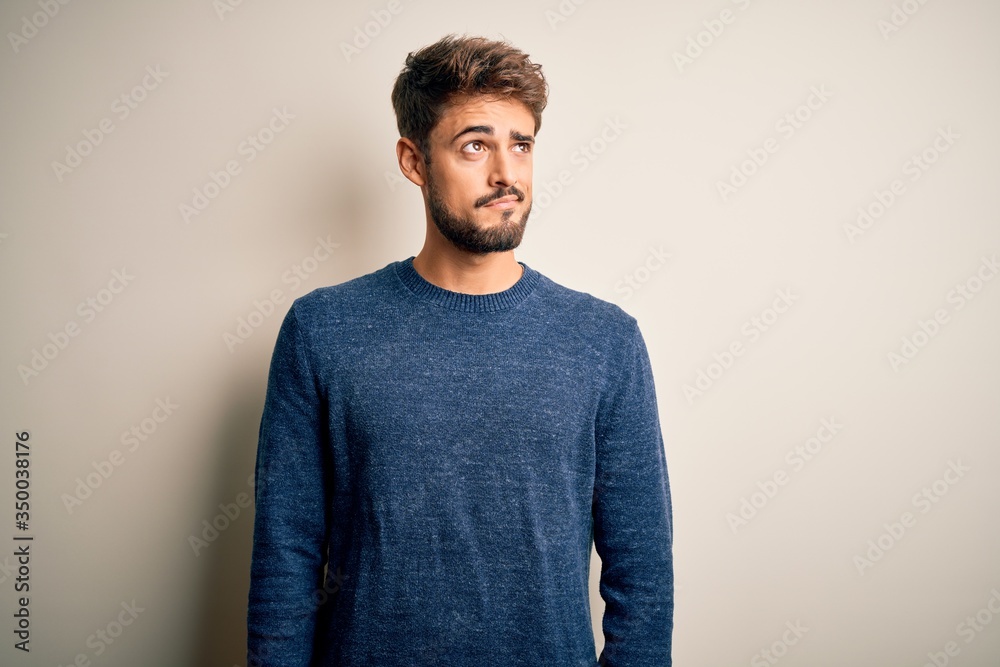 Young handsome man with beard wearing casual sweater standing over white background smiling looking to the side and staring away thinking. Young handsome man with beard wearing casual sweater standing over white background smiling looking to the side and staring away thinking.