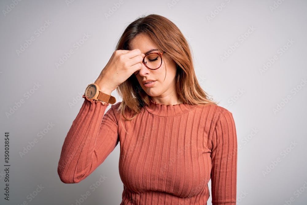 Young beautiful brunette woman wearing casual sweater and glasses over white background tired rubbing nose and eyes feeling fatigue and headache. Stress and frustration concept. Young beautiful brunette woman wearing casual sweater and glasses over white background tired rubbing nose and eyes feeling fatigue and headache. Stress and frustration concept.