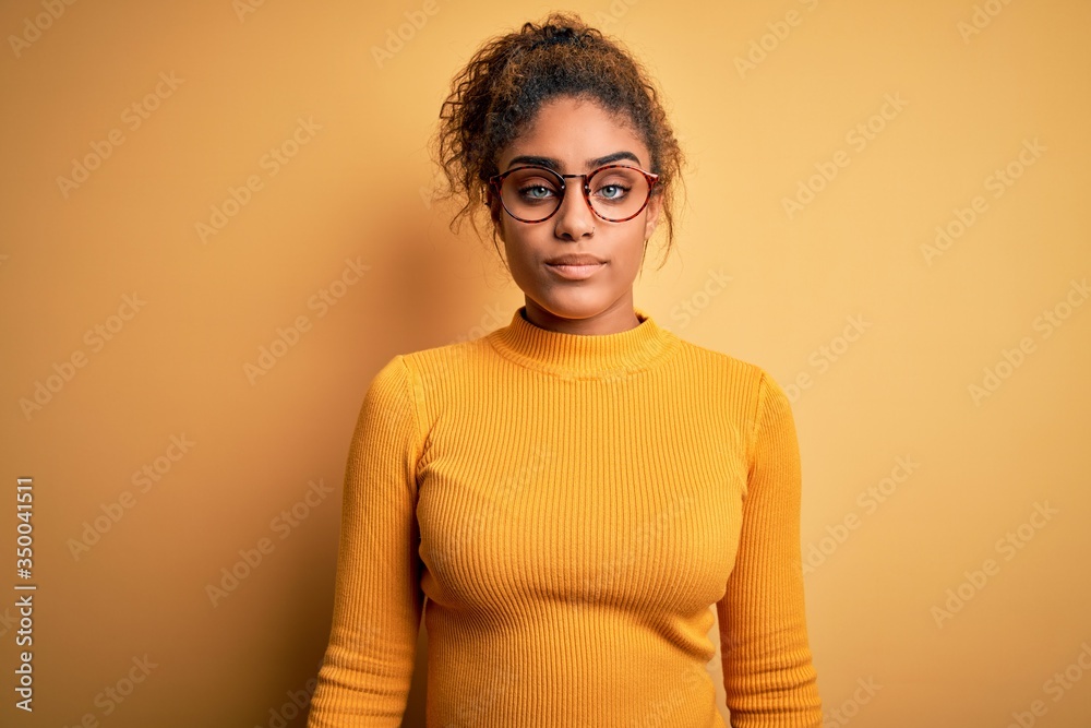 Young beautiful african american girl wearing sweater and glasses over yellow background looking sleepy and tired, exhausted for fatigue and hangover, lazy eyes in the morning. Young beautiful african american girl wearing sweater and glasses over yellow background looking sleepy and tired, exhausted for fatigue and hangover, lazy eyes in the morning.