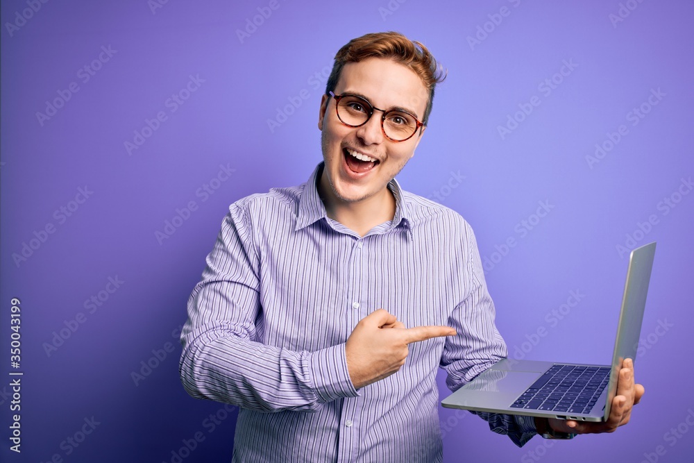 Young handsome redhead businessman working using laptop over purple background very happy pointing with hand and finger Young handsome redhead businessman working using laptop over purple background very happy pointing with hand and finger