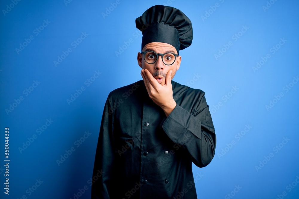 Young handsome chef man wearing cooker uniform and hat over isolated blue background Looking fascinated with disbelief, surprise and amazed expression with hands on chin Young handsome chef man wearing cooker uniform and hat over isolated blue background Looking fascinated with disbelief, surprise and amazed expression with hands on chin
