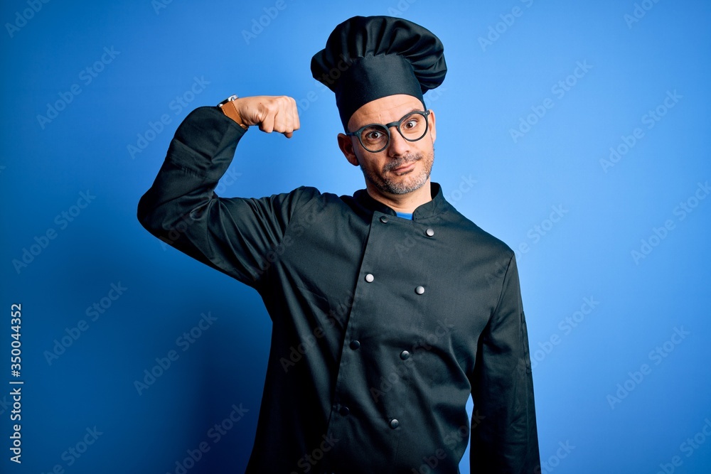 Young handsome chef man wearing cooker uniform and hat over isolated blue background Strong person showing arm muscle, confident and proud of power Young handsome chef man wearing cooker uniform and hat over isolated blue background Strong person showing arm muscle, confident and proud of power