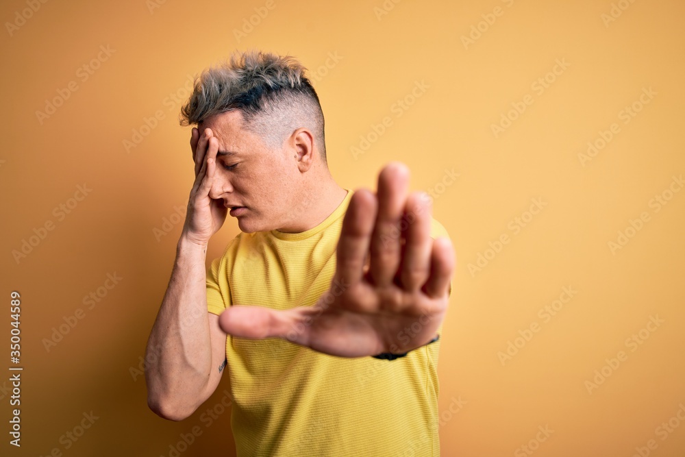 Young handsome modern man wearing yellow shirt over yellow isolated background covering eyes with hands and doing stop gesture with sad and fear expression. Embarrassed and negative concept. Young handsome modern man wearing yellow shirt over yellow isolated background covering eyes with hands and doing stop gesture with sad and fear expression. Embarrassed and negative concept.