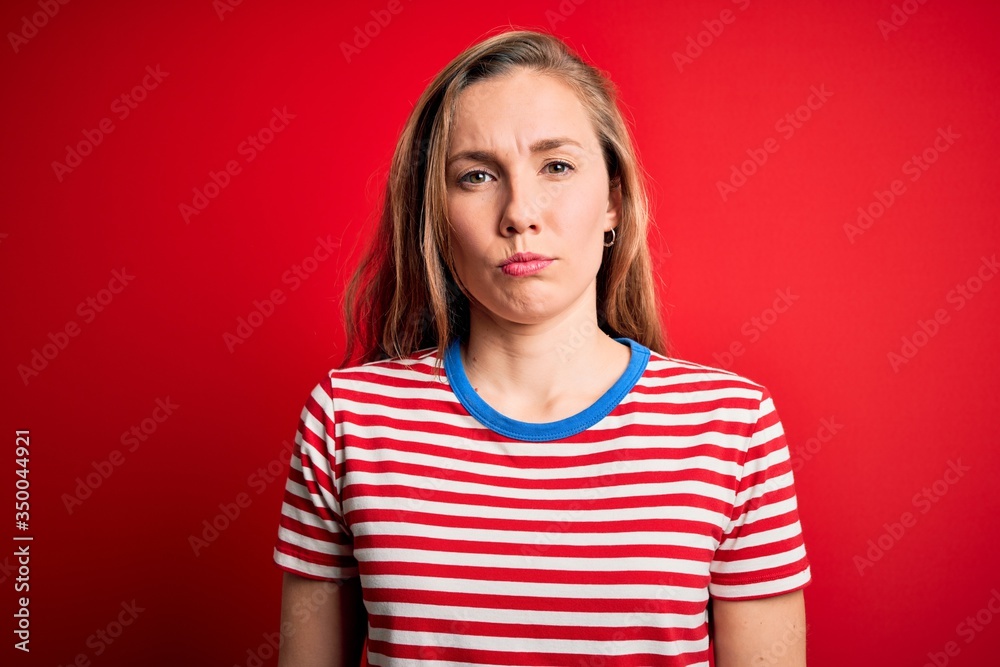 Young beautiful blonde woman wearing casual striped t-shirt over isolated red background depressed and worry for distress, crying angry and afraid. Sad expression. Young beautiful blonde woman wearing casual striped t-shirt over isolated red background depressed and worry for distress, crying angry and afraid. Sad expression.