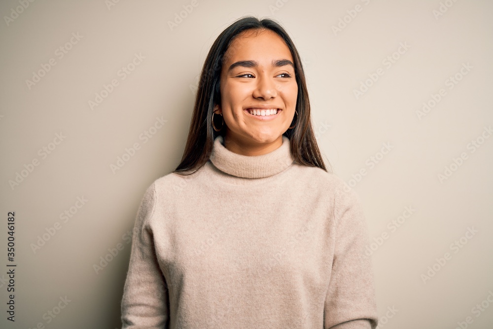 Young beautiful asian woman wearing casual turtleneck sweater over white background looking away to side with smile on face, natural expression. Laughing confident. Young beautiful asian woman wearing casual turtleneck sweater over white background looking away to side with smile on face, natural expression. Laughing confident.