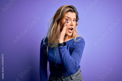 Young beautiful blonde woman wearing casual t-shirt over isolated purple background hand on mouth telling secret rumor, whispering malicious talk conversation