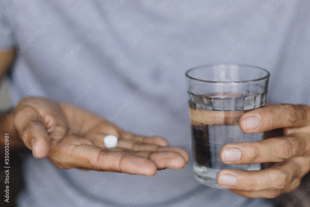 Sick man with a glass of water and pills, Taking medication to alleviate illness Sick man with a glass of water and pills, Taking medication to alleviate illness