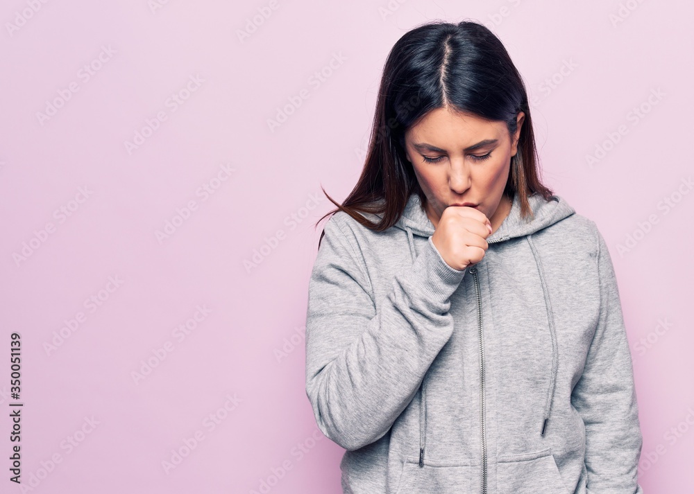 Young beautiful sporty woman wearing sportswear standing over isolated pink background feeling unwell and coughing as symptom for cold or bronchitis. Health care concept. Young beautiful sporty woman wearing sportswear standing over isolated pink background feeling unwell and coughing as symptom for cold or bronchitis. Health care concept.