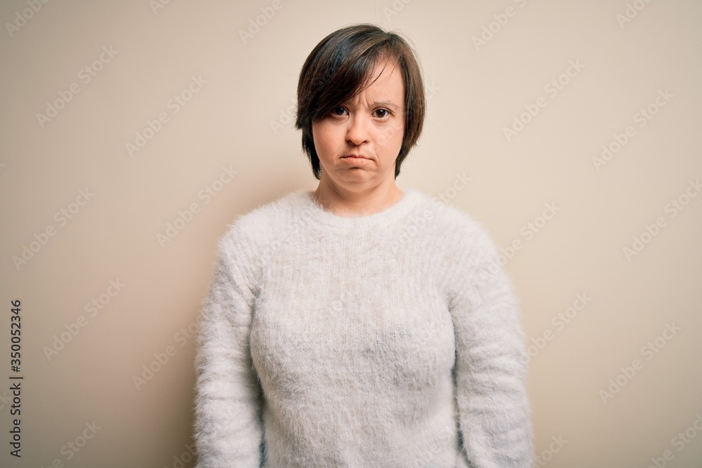 Young down syndrome woman standing over isolated background depressed and worry for distress, crying angry and afraid. Sad expression. Young down syndrome woman standing over isolated background depressed and worry for distress, crying angry and afraid. Sad expression.