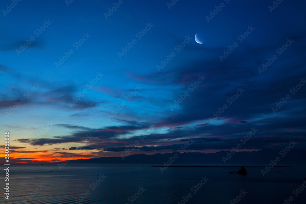 夜明けの月と暁に染まる海