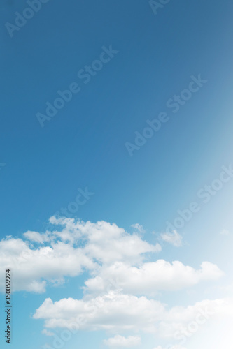 Beautiful sunny blue sky background with cotton candy   puffy fluffy white cumulus clouds on bright daylight horizon in tropical summer or spring sunlight   sun rays at sunshine day  copy free space 