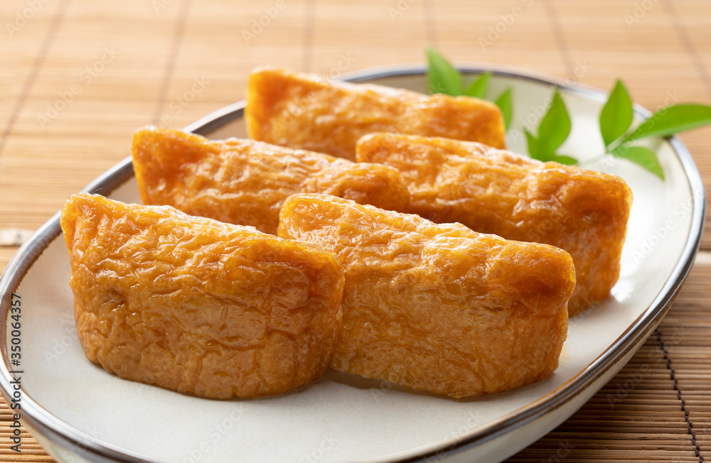 Japanese Inari Sushi on a plate set against a wooden backdrop Japanese Inari Sushi on a plate set against a wooden backdrop