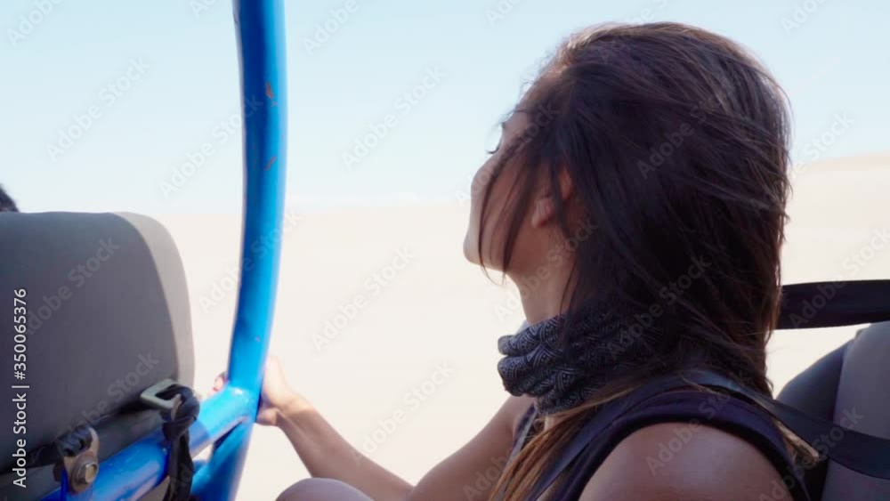 Close-up slow motion of young woman traveling in dune buggy at desert, she is on vacation - Huacachina, Peru