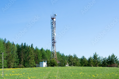 Cellular repeater tower on blue sky background. Spring landscape.
