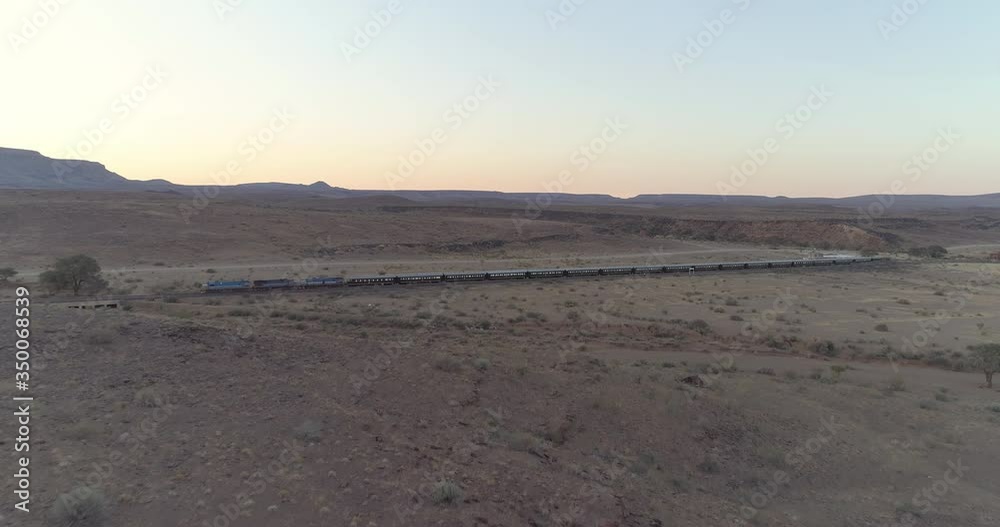 Aerial view of passenger train at desert against clear sky during sunset, drone moving forward over landscape - Swakopmund, Namibia Aerial view of passenger train at desert against clear sky during sunset, drone moving forward over landscape - Swakopmund, Namibia