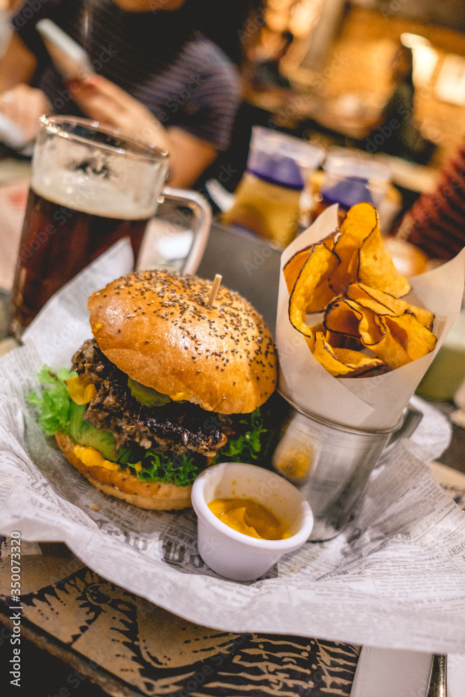 Dark craft beer shop and vegan mushroom burguuer with fried sweet potatos over a paper tablecloth Dark craft beer shop and vegan mushroom burguuer with fried sweet potatos over a paper tablecloth