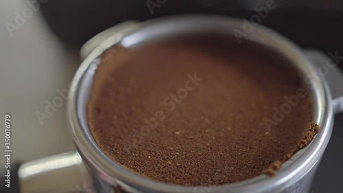 Close up overhead of a barista tamping fresh ground coffee