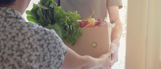 Man wearing gloves home delivering food box, volunteer holding grocery box for donation, supporting local community business concept