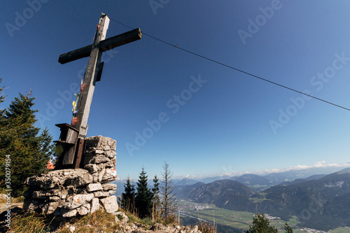 Cross at the top of a hiking trail on the outskirts of Brandenberg with the Inntal valley visible in the distance. Tyrol, Austria photo