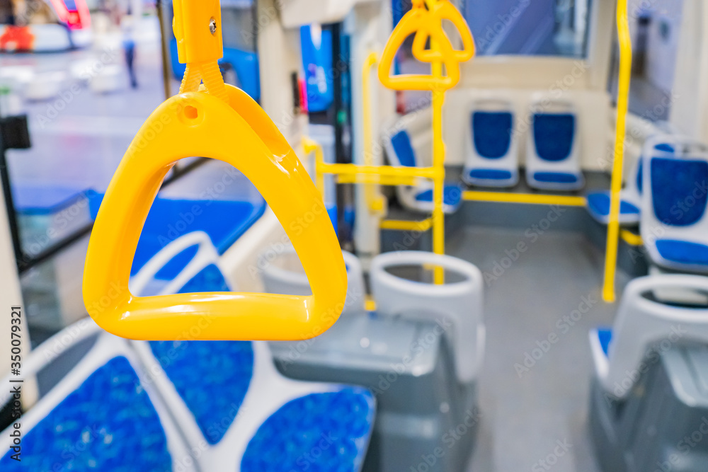 Yellow handles for passengers in the passenger compartment of a city bus close-up. Empty interior of the vehicle. Transportation of passengers within the city. Yellow hanging handles and handrails.