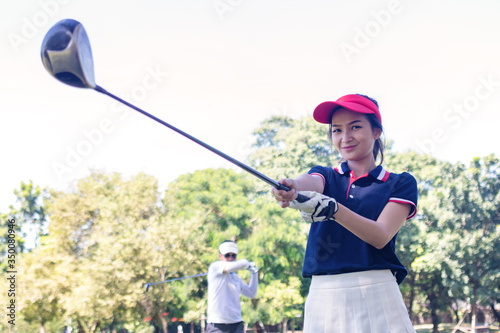 Portrait Asia woman play golf.She is playing golf on a sunny day. Hitting, scenery, beautiful golf girl, game, pastime.Photo concept Portrait sport and money.