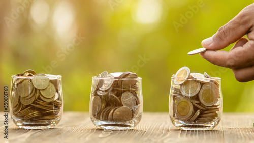 Coin in clear jar and piggy bank (Home Model) on green nature blur background. Money savings for home concept photo