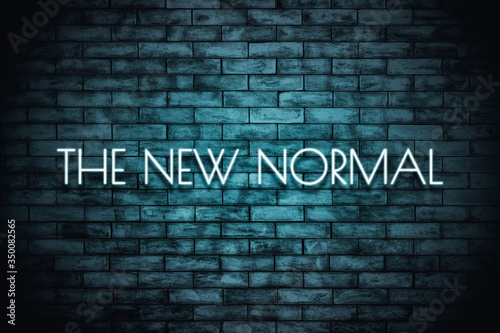 The New Normal. Neon light lettering on brickwall background. New normal after covid-19 pandemic Background concept for poster, social network, banner, cards.