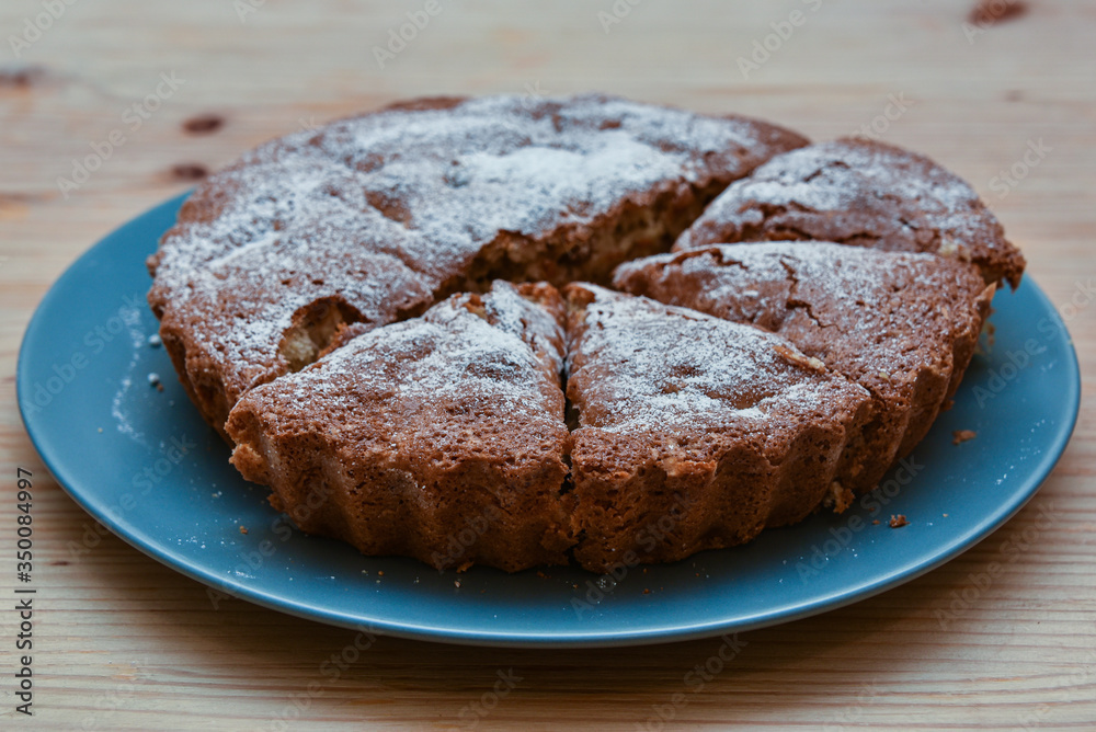 homemade cake with icing sugar on a plate on a wooden table homemade cake with icing sugar on a plate on a wooden table