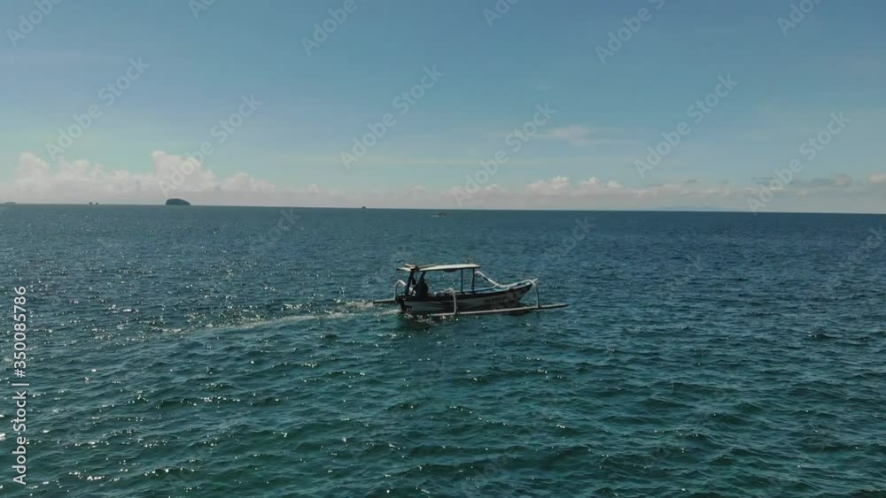 View drone around on a rocking fishing boat going to the ocean near Bali island on a sunny day in Bali, Indonesia View drone around on a rocking fishing boat going to the ocean near Bali island on a sunny day in Bali, Indonesia