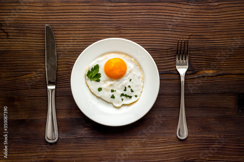 Fried eggs on plate - dark wooden kitchen table top-down