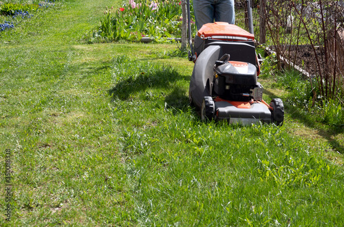 Man moves with lawnmower mows green grass