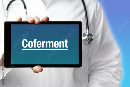 Coferment. Arzt mit Stethoskop hält Tablet-Computer in Hand. Text im Display. Blauer Hintergrund. Krankheit, Gesundheit, Medizin