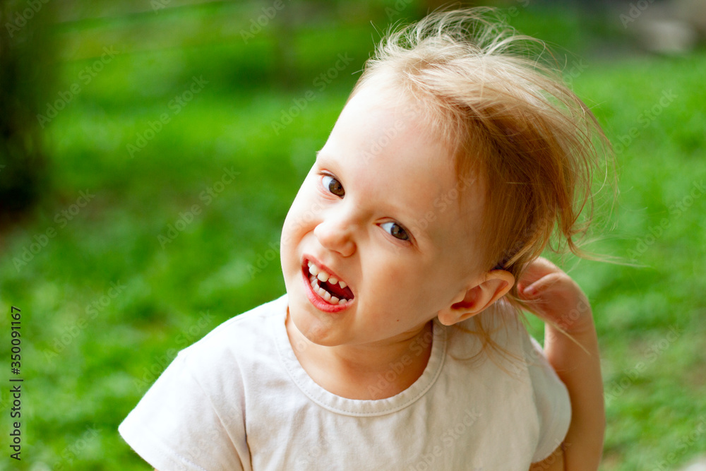 Portrait of cute blond toddler girl in a windy summer day making faces and showing white teeth. Portrait of cute blond toddler girl in a windy summer day making faces and showing white teeth.