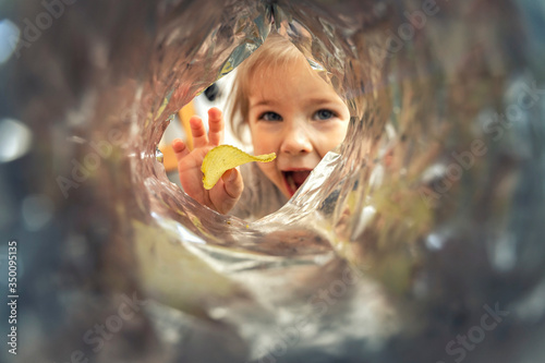 little girl 4 years old takes out potato chips from a pack, view from a pack on a child