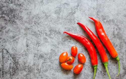 Top viwe tomatoes and Red chilli on a stone background