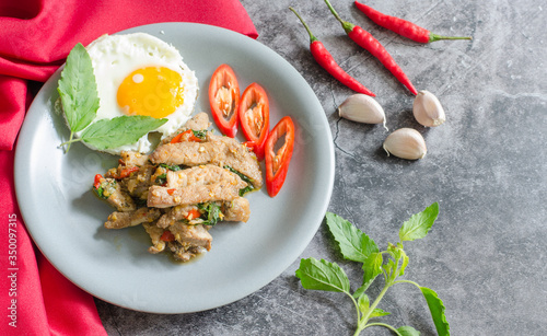 Thai stir-fried pig with fried egg and basil with raw materials are basil leaves, red chili and garlic. still life image. thai food concept.with copy space for your text.
