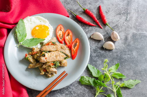 Thai stir-fried pig with fried egg and basil with raw materials are basil leaves, red chili and garlic. still life image. thai food concept.with copy space for your text.