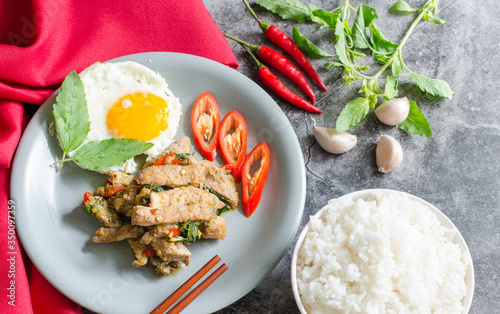 Thai stir-fried pig with fried egg, ready rice and basil with raw materials are basil leaves, red chili and garlic. still life image. thai food concept.with copy space for your text.