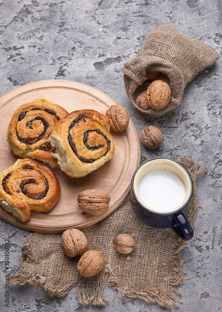 Basket of homemade buns with jam, served on old wooden table with walnuts and cup of milk Basket of homemade buns with jam, served on old wooden table with walnuts and cup of milk