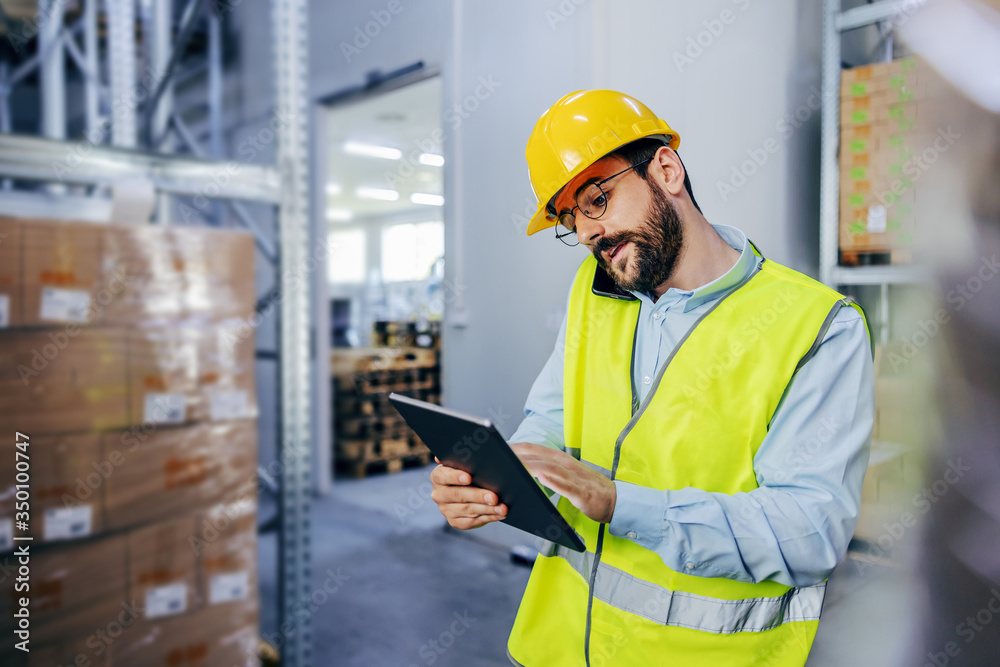 Young hardworking supervisor talking on the phone and using tablet to report problem in warehouse. Young hardworking supervisor talking on the phone and using tablet to report problem in warehouse.