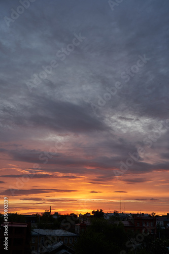 A beautiful evening blue sky at sunset with flaming bright light clouds. Warm evening. © nikolay_alekhin