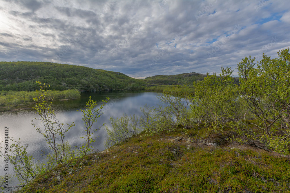 The reservoir is surrounded by hills and forest.Clouds are reflected in the water.Summer landscape.