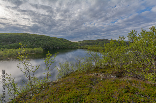 The reservoir is surrounded by hills and forest.Clouds are reflected in the water.Summer landscape.