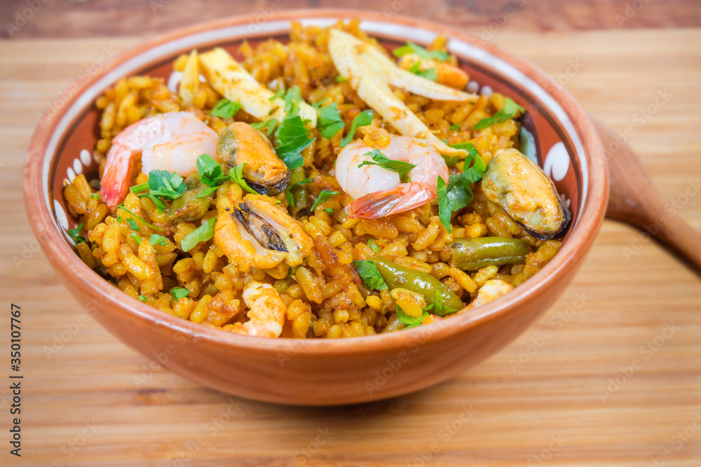 Cooked seafood paella in bowl close-up in selective focus