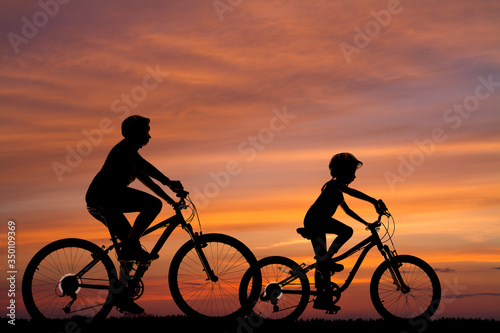 silhouettes of two cyclists against the background of the sunset