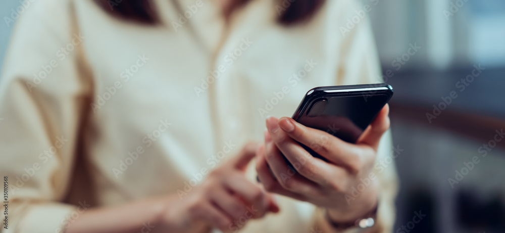 Closeup of young woman hand holding smartphone and chatting with friends at social network.