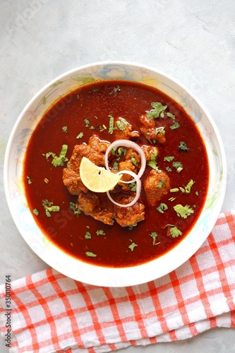 Indian Food- Kolhapuri Mutton tambda rassa or red meat curry is authentic Kolhapur’s very spicy lamb gravy dish. Cooked with Indian spices & garnished with coriander, onion & lemon wedge. Copy space. photo