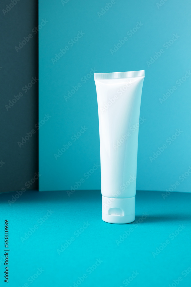 Moisturizer hand cream white plastic tube mockup on blue trendy paper background. Blank body and health care beauty product packaging Moisturizer hand cream white plastic tube mockup on blue trendy paper background. Blank body and health care beauty product packaging