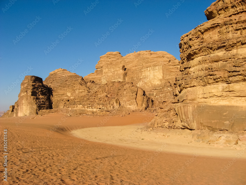 Picturesque rocks of Wadi rum in the Jordanian part of the Arabian desert among orange and yellow sand.